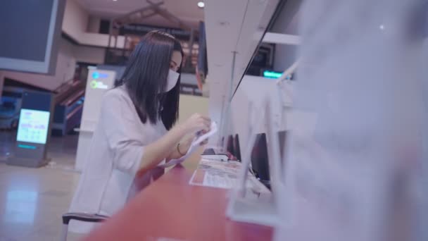 Junge Asiatinnen geben Reisedokumente beim Schalterpersonal im Flughafenterminal ab, Fluggastkarte der Fluggesellschaften, Covid-19-Epidemie, neue soziale Distanzierung von Reisen, Luftfahrtindustrie  - Filmmaterial, Video