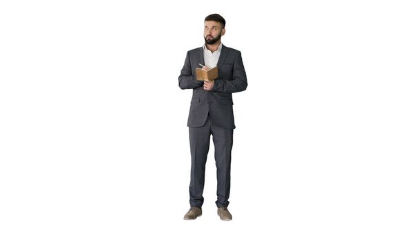 Concentrated young man in formalwear holding note pad and writin - Foto, imagen