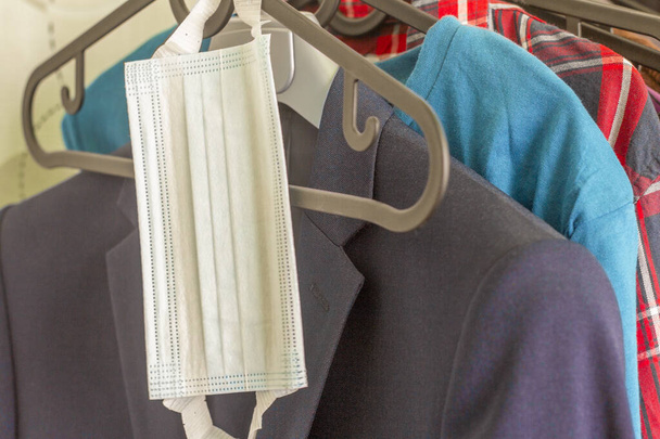 A protective surgical mask hangs on a clothes rack.Protection from viruses and infections when leaving the house.Element of the wardrobe. - Photo, Image