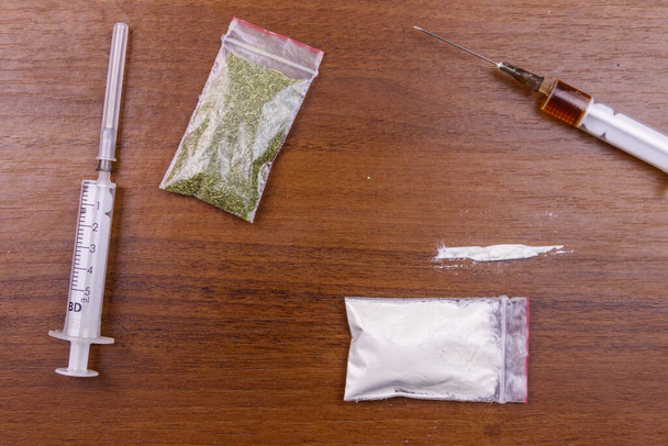 Différents types de drogues : cocaïne, seringue d'héroïne et cannabis séché sur une table. Consommation de drogues, criminalité et toxicomanie
 - Photo, image