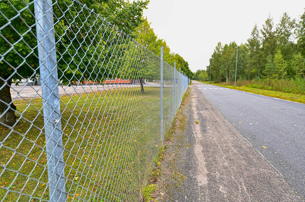 egyenes fém kerítés mellett aszfalt út Svédországban - Fotó, kép