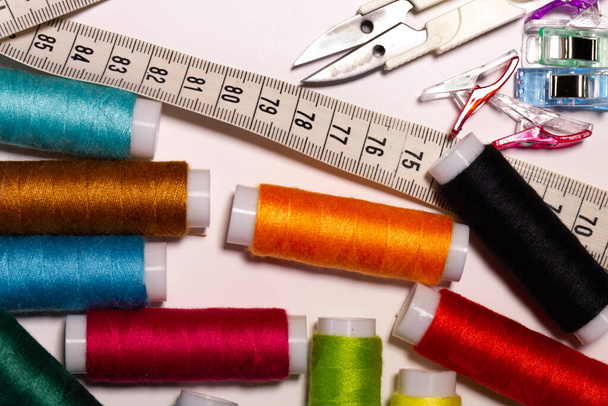 Herramientas de coser, tijeras, hilos, cinta métrica y accesorios sobre fondo blanco - Foto, Imagen