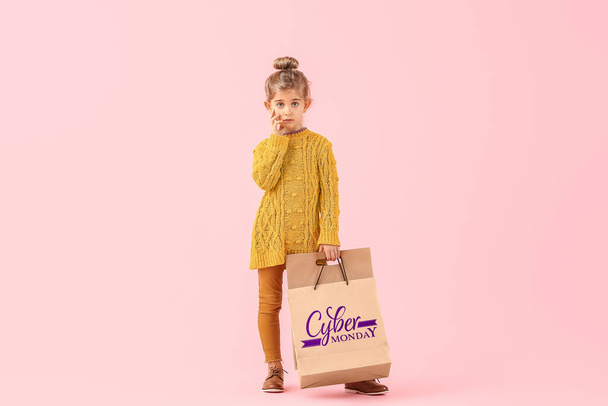 Милая маленькая девочка с пакетами для покупок на цветном фоне. Концепция киберпонедельника - Фото, изображение