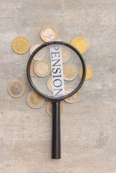 Word PENSION mit Münzen und Lupe auf grauem Hintergrund - Foto, Bild