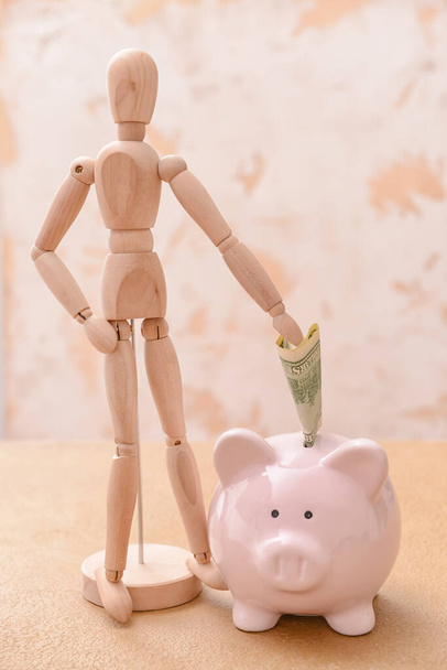 Банк свиней с манекеном и деньгами на столе. Концепция пенсионного обеспечения - Фото, изображение