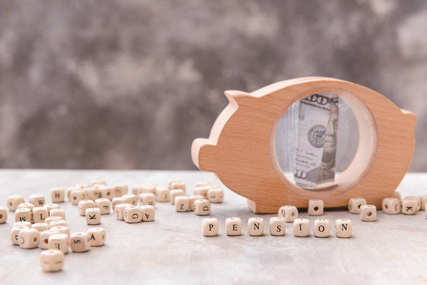 Свинячий банк з грошима і кубиками зі словом PENSION на сірому фоні
 - Фото, зображення
