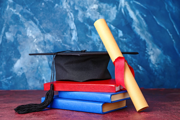 Afstudeerhoed, diploma en boeken over kleur achtergrond - Foto, afbeelding