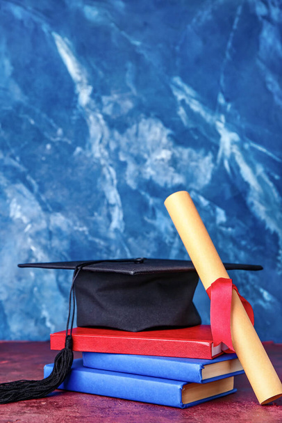 Afstudeerhoed, diploma en boeken over kleur achtergrond - Foto, afbeelding