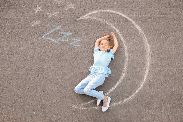 Mała dziewczynka leżąca w pobliżu kredy rysunek księżyca na zewnątrz - Zdjęcie, obraz