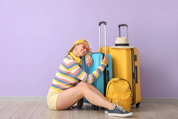 Egy fiatal nő bőröndökkel a színes fal mellett. Utazási koncepció - Fotó, kép