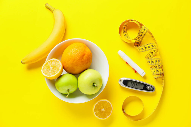 Φρούτα, μεζούρα, στυλό και γλυκομετρητής σε έγχρωμο φόντο. Έννοια διαβήτη - Φωτογραφία, εικόνα