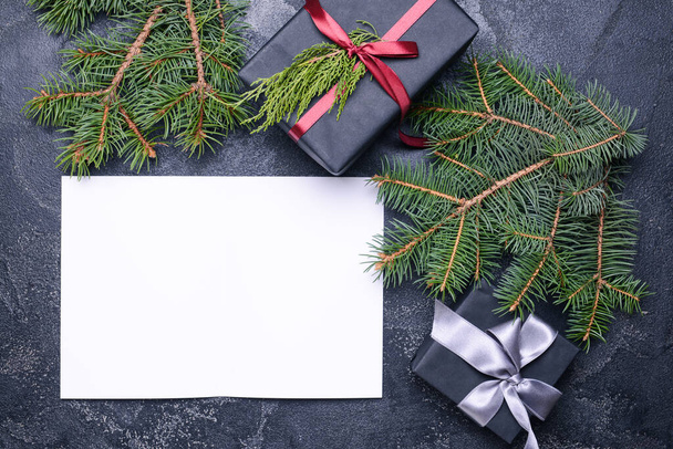 Gyönyörű karácsonyi ajándékok és üres kártya sötét háttér - Fotó, kép