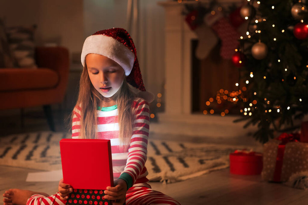 Cute little girl with Christmas gift at home in evening - Photo, image
