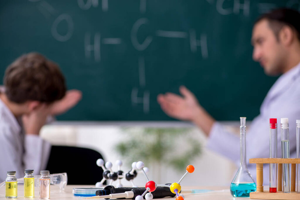 Young chemistry teacher and schoolboy in the classroom - Photo, image