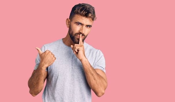 Young hispanic man wearing casual clothes asking to be quiet with finger on lips pointing with hand to the side. silence and secret concept.  - Fotoğraf, Görsel
