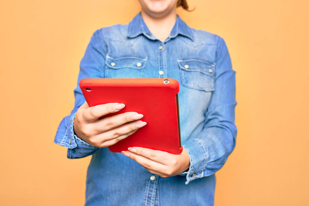 Jonge blanke vrouw die werkt met een tablet die over geïsoleerde gele achtergrond staat - Foto, afbeelding
