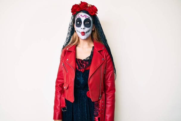 Woman wearing day of the dead costume over white making fish face with lips, crazy and comical gesture. funny expression.  - 写真・画像