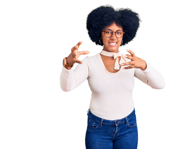 jong Afrikaans amerikaans meisje dragen casual kleding en bril schreeuwen gefrustreerd door woede, handen proberen te wurgen, schreeuwen gek  - Foto, afbeelding