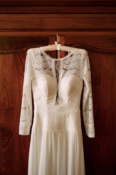 Sukienka ślubna z koronką na brązowych drewnianych drzwiach. - Zdjęcie, obraz