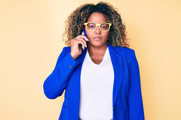 Молода афроамериканка плюс розмір жінка в окулярах розмовляє на смартфоні мислення ставлення і тверезий вираз виглядає впевнено
  - Фото, зображення