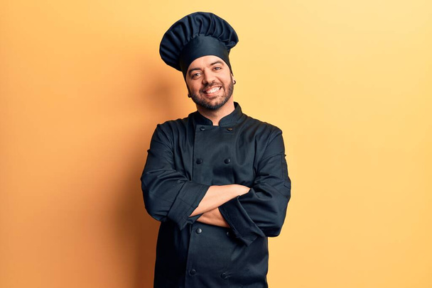 Young hispanic man wearing cooker uniform happy face smiling with crossed arms looking at the camera. positive person.  - Foto, Bild