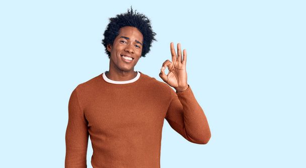 Komea afrikkalainen amerikkalainen mies afro hiukset yllään rento vaatteita hymyillen positiivinen tekee ok merkki käsin ja sormin. onnistunut ilmaisu.  - Valokuva, kuva