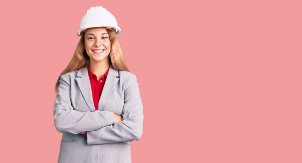Beautiful young woman wearing architect hardhat happy face smiling with crossed arms looking at the camera. positive person.  - Fotoğraf, Görsel