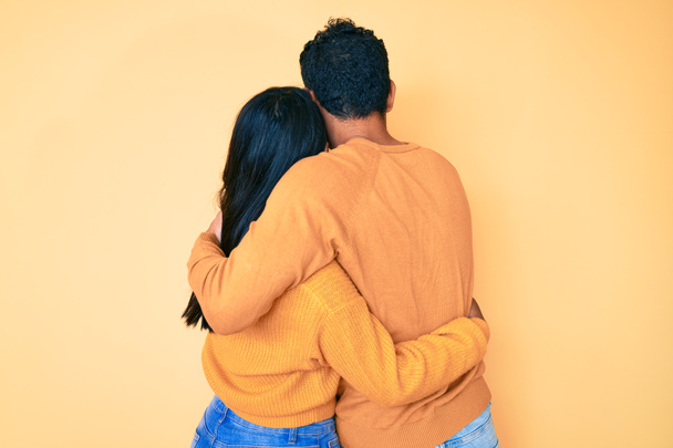Hermosa pareja latina joven usando ropa casual juntos abrazándose a uno mismo feliz y positivo desde atrás. amor propio y cuidado personal  - Foto, Imagen