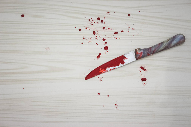 Bloederig mes op de grond. Het mes werd gevonden op de plaats delict. Een forensisch team neemt bloedmonsters van het mes. Bloederig mes ligt op keramische tegels achtergrond. Begrip binnenlandse moorden. - Foto, afbeelding