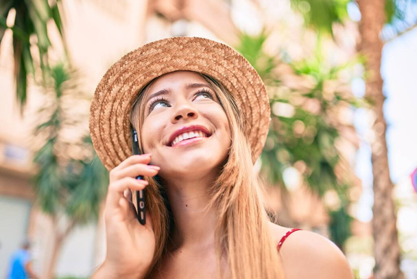 jong Kaukasisch toeristisch meisje glimlachen gelukkig praten smartphone in de stad. - Foto, afbeelding