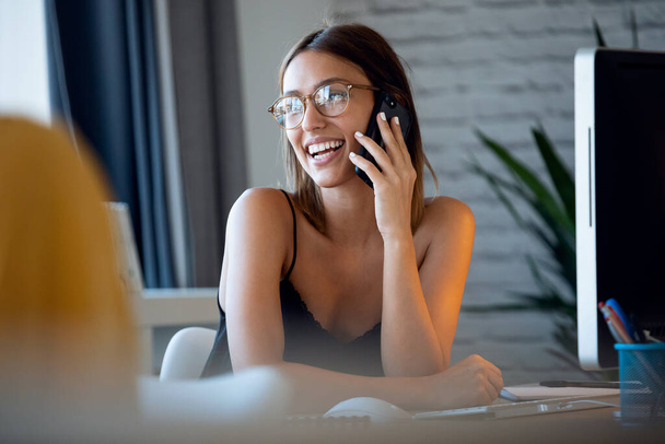 Portrait of happy freelance business woman seller talking with her mobile phone while working with computer in her startup small business.  - Φωτογραφία, εικόνα