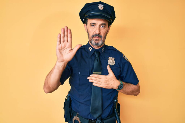 Середньовіччя іспаномовний чоловік в поліцейській формі лаявся рукою на грудях і відкритій долоні, роблячи клятву обіцянки вірності
  - Фото, зображення