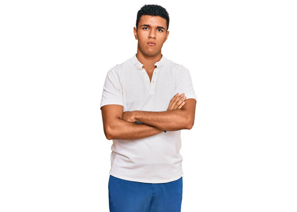 Mladý arabský muž v neformálním oblečení skeptický a nervózní, nesouhlasný výraz na tváři se zkříženýma rukama. negativní osoba.  - Fotografie, Obrázek