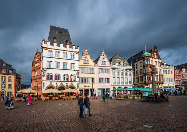 TRIER, ALEMANHA - OUTUBRO 11, 2019: Casas góticas coloridas sob o céu dramático. Old Market Square em Trier, Alemanha. Trier é um destino de viagem popular e Patrimônio Mundial da UNESCO - Foto, Imagem