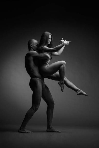 Photo en noir et blanc d'une paire de danseurs dans une élégante pose acrobatique sur un fond sombre. - Photo, image