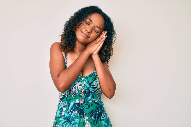 Jeune femme afro-américaine portant des vêtements décontractés dormir fatigué rêver et posant avec les mains ensemble tout en souriant avec les yeux fermés.  - Photo, image