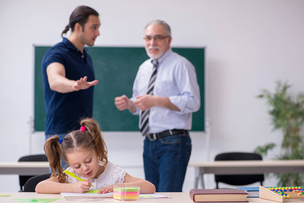 Jonge ouder, oude mannelijke leraar en klein meisje in de klas - Foto, afbeelding