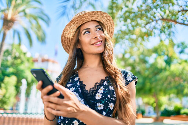Mulher hispânica jovem em férias usando smartphone na rua da cidade. - Foto, Imagem