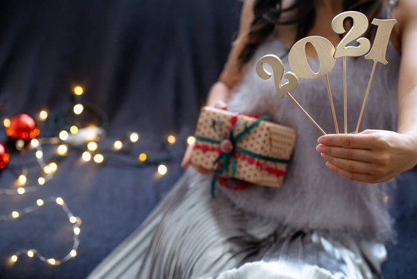 2021 New Year. Wooden number in girls hands on background with gift box - 写真・画像