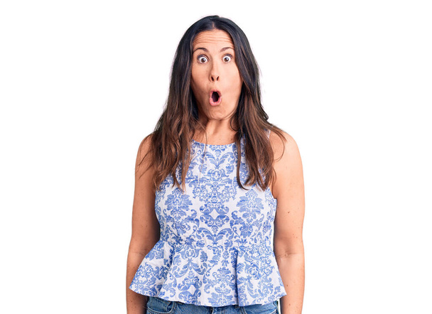 Young beautiful brunette woman wearing casual t-shirt afraid and shocked with surprise expression, fear and excited face.  - Photo, Image