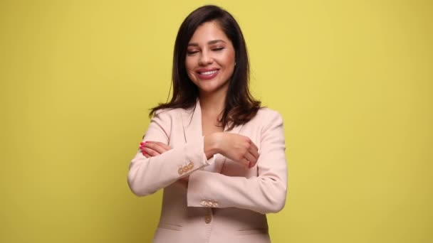 νεαρή επιχειρηματίας με ένα μεγάλο χαμόγελο στο πρόσωπό της σταυρώνει τα χέρια της και κοιτάζοντας την κάμερα στο κίτρινο φόντο - Πλάνα, βίντεο