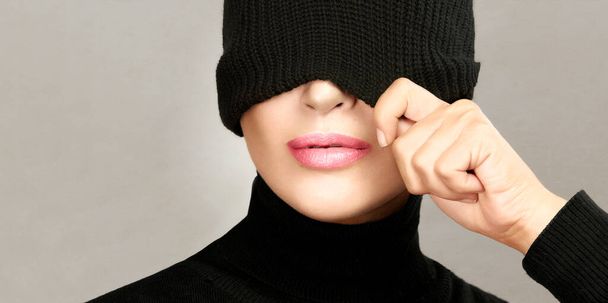 Φθινοπωρινή ιδέα Όμορφη νεαρή γυναίκα με λείο υγιές δέρμα και γυμνό μακιγιάζ σε ένα μαύρο μάλλινο φθινοπωρινό ντύσιμο με το σκουφί καπέλο τράβηξε πάνω από τα μάτια της σε ένα περικοπή πανόραμα εποχιακό πορτρέτο με copyspace - Φωτογραφία, εικόνα