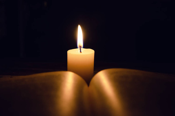 Płonący świeca i księga na stół w ciemność na drewniany stół. Pojęcie wiedzy, religii, magii - Zdjęcie, obraz
