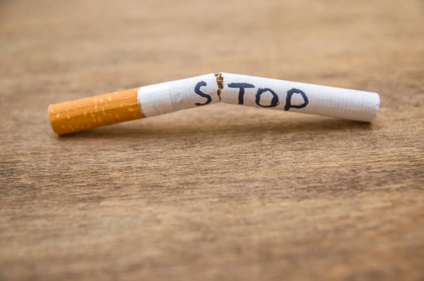 broken cigarette with the word stop on wooden background; stop smoking close concept; space for text - Photo, Image