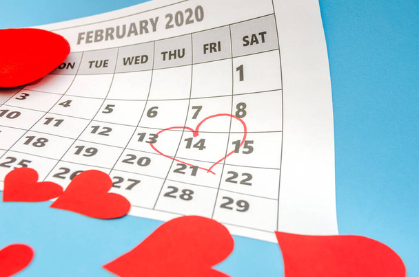 Ystävänpäivä 14 on merkitty sydämellä kalenteriin, paperi sydämet ovat hajallaan ympäri. Loma-ajatus - Valokuva, kuva