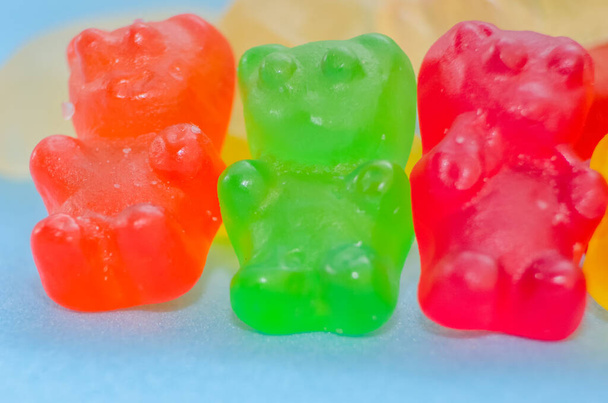 Dois ursos de marmelada estão entre outros ursos de marmelada em um fundo azul, macro - Foto, Imagem
