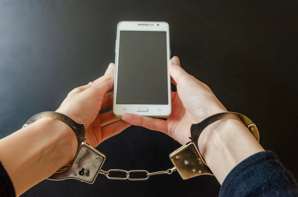 Заарештована жінка в наручниках, тримаючи смартфон
 - Фото, зображення