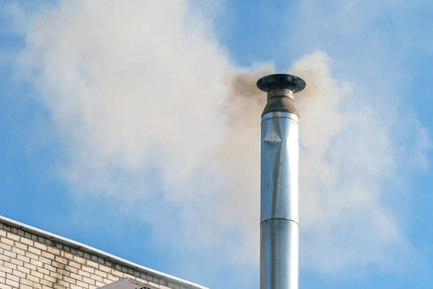 Smoke from the chimney against the blue sky. Pipe with smoke. Emissions of pipes into the atmosphere. Harmful emissions into the atmosphere. concept of ecology - Photo, Image