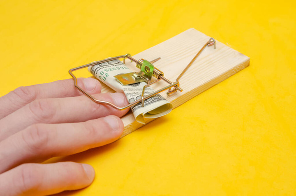 Hand in a mousetrap with money on a yellow background. concept of a bribe - Photo, Image