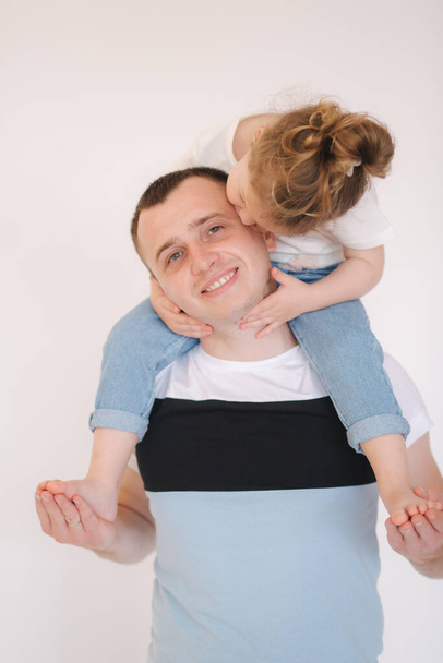 Portrait of little girl with her dad. Cute little daughter with father in studio. Daughter kiss dad in cheek - Photo, Image
